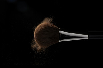 Horizontal makeup brush in motion on black background