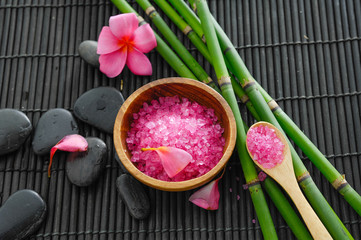 Obraz na płótnie Canvas Spa setting with many salt in bowl, stone, bamboo grove ,frangipani on mat