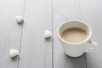 Coffee cup with milk and sugar cubes scattered