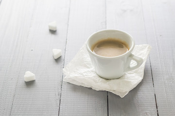 Coffee cup with milk and sugar cubes scattered