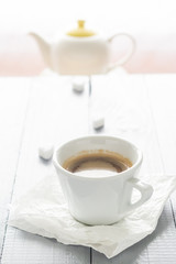 Coffee cup with milk and sugar cubes scattered
