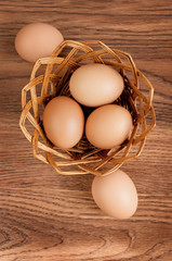 Eggs in a basket on wooden table. Top view