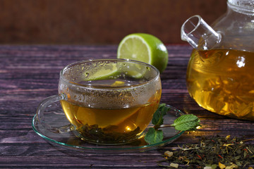 Tea in a glass teapot and a transparent cup with lime and mint o