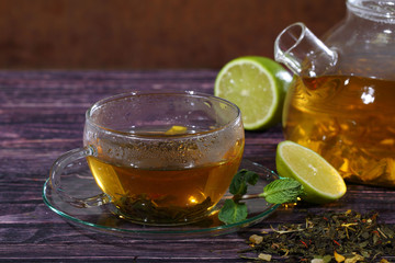 Tea in a glass teapot and a transparent cup with lime and mint o