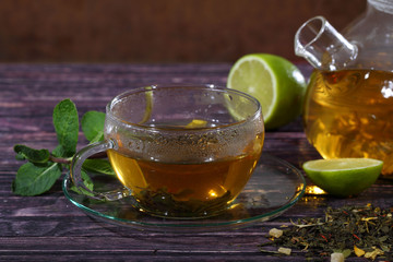Tea in a glass teapot and a transparent cup with lime and mint o