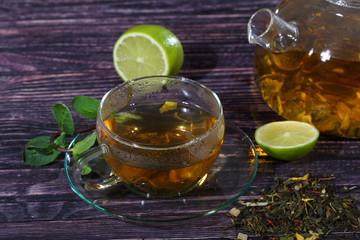 Tea in a glass teapot and a transparent cup with lime and mint o