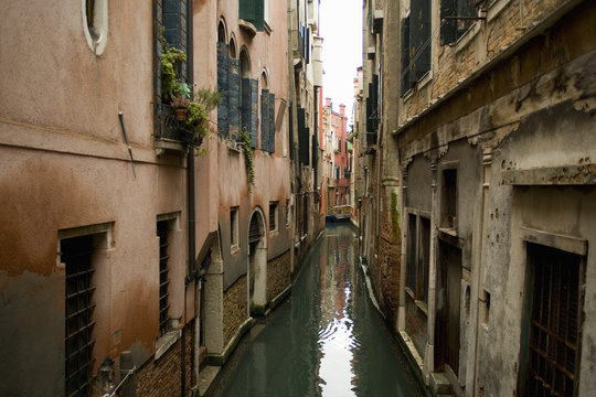 A view from above of a quiet backwater, a narrow canal with historic buildings rising from the water. 