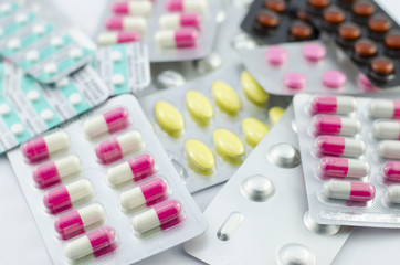 Capsules and pills packed on white background