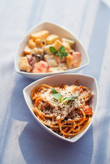 White bowl of fresh healthy fruit salad and spaghetti