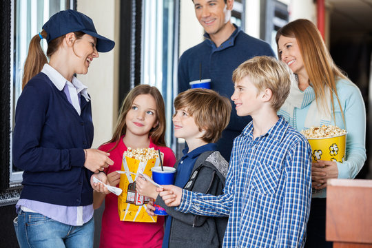 Happy Worker Checking Tickets Of Family At Cinema