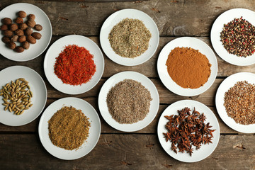 Different spices on plates, on old wooden table