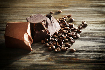 Chocolate bars with coffee beans on wooden background