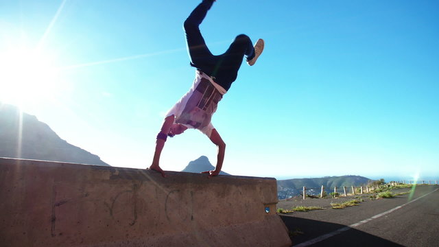 Breakdancer testing his fitness and strength by balancing on a wall