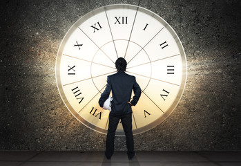 businessman stand against sun light through clock glass, busines
