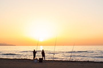 Men fishing on sea beach at sunset - 80456636