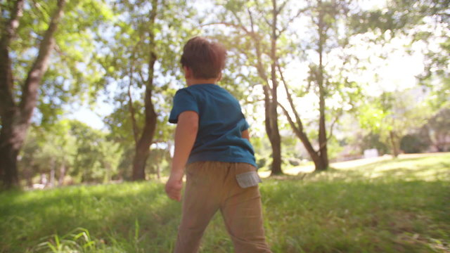 Adventurous little boy running through field exploring and loving childhood