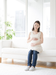 ソファに座る若い妊婦