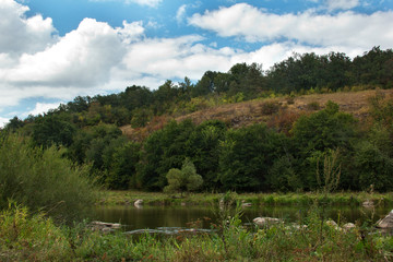 Fototapeta na wymiar landscape of a green grassy hills, trees, river and sky