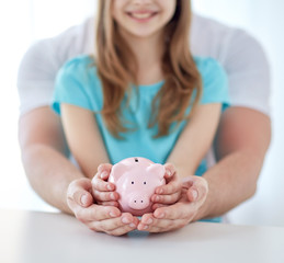close up of family hands with piggy bank