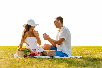 smiling couple with small red gift box on picnic