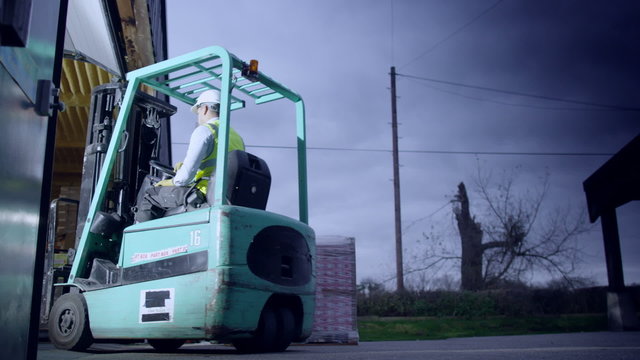 A warehouse worker drives a forklift truck into an open warehouse