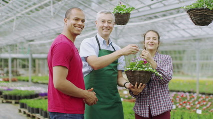 Plant nursery worker helping couple who are shopping for plants at garden centre - Powered by Adobe