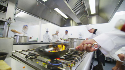Professional chef in a commercial kitchen cooking flambe style