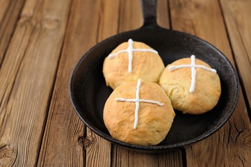 Hot cross buns in cast iron skillet on wooden background