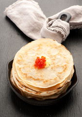 Pancakes with red caviar in frying pan