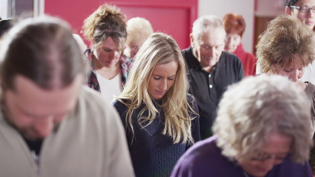 Church group bow their heads in prayer