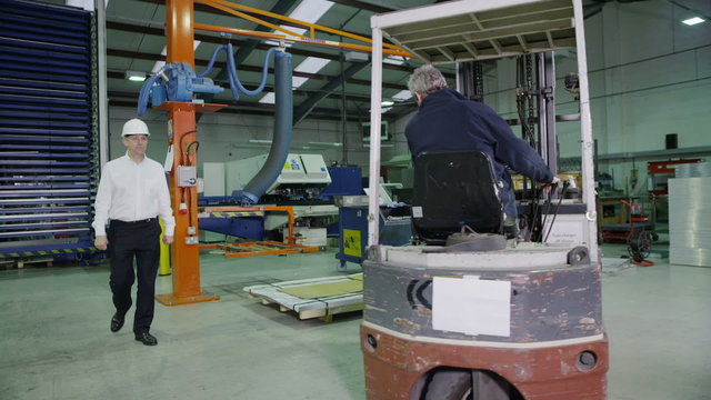 Team of busy warehouse workers lifting and moving empty wooden pallets