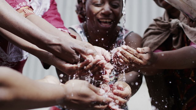 Stream of fresh water and the hands of people from a poor community