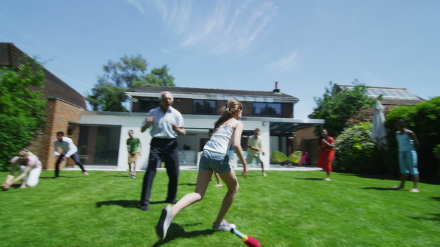 Family & friends of many generations playing sports in the garden on a sunny day