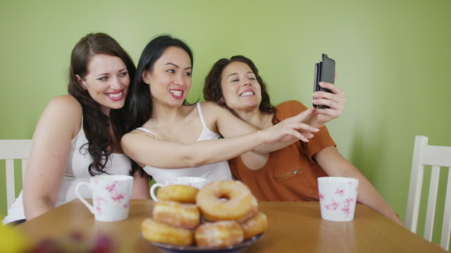 Female friends having coffee pose to take a picture with mobile phone