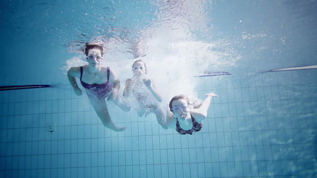 Young female friends in a swimming pool having fun together underwater