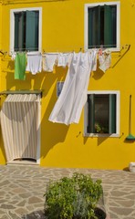 Wash clothes hanging on yellow facade in Burano, Venice, Italy