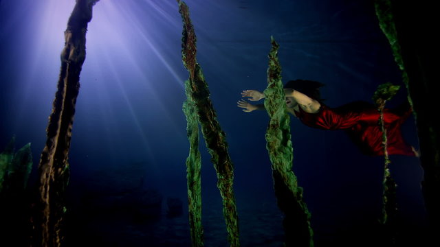 Beautiful mysterious underwater woman in red dress