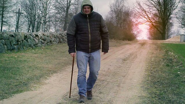 Man with walking stick on the rural road