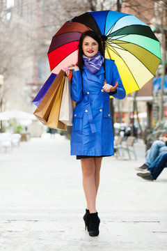  woman in blue with shopping bags and umbrella  at  street