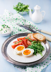 Breakfast with soft-boiled egg, arugula and tomatoes