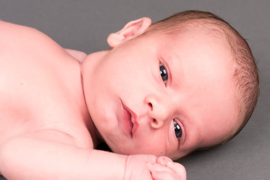 Closeup Of Newborn Baby With Wide Open Eyes.