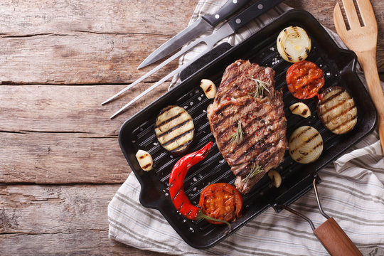 grilled beef steak with vegetables in pan. horizontal top view