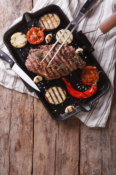 grilled beef steak with vegetables in pan. Vertical top view