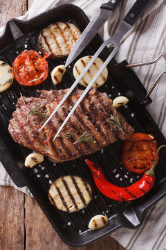 grilled beef steak on the grill pan closeup, vertical top view