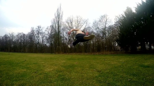 Guy jumps backflip in the park, slowmotion