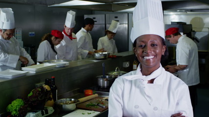 Portrait of smiling head chef and her staff in a commercial kitchen