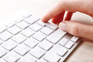 Female hand with keyboard on wooden desktop background