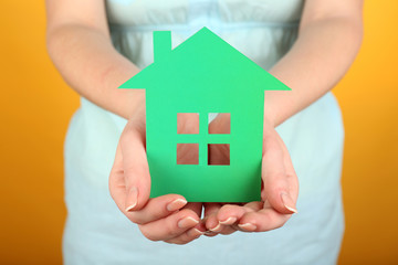 Cutout house in female hand on colorful background