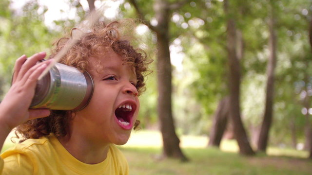 Little boy listening to sound through a tin can phone