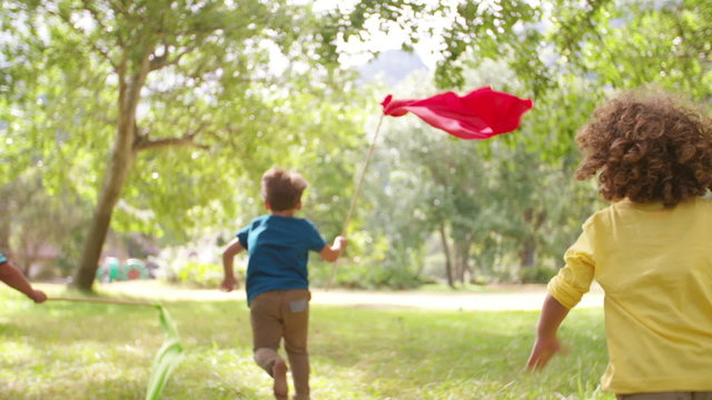 Children playing and running in a park with colorful banners